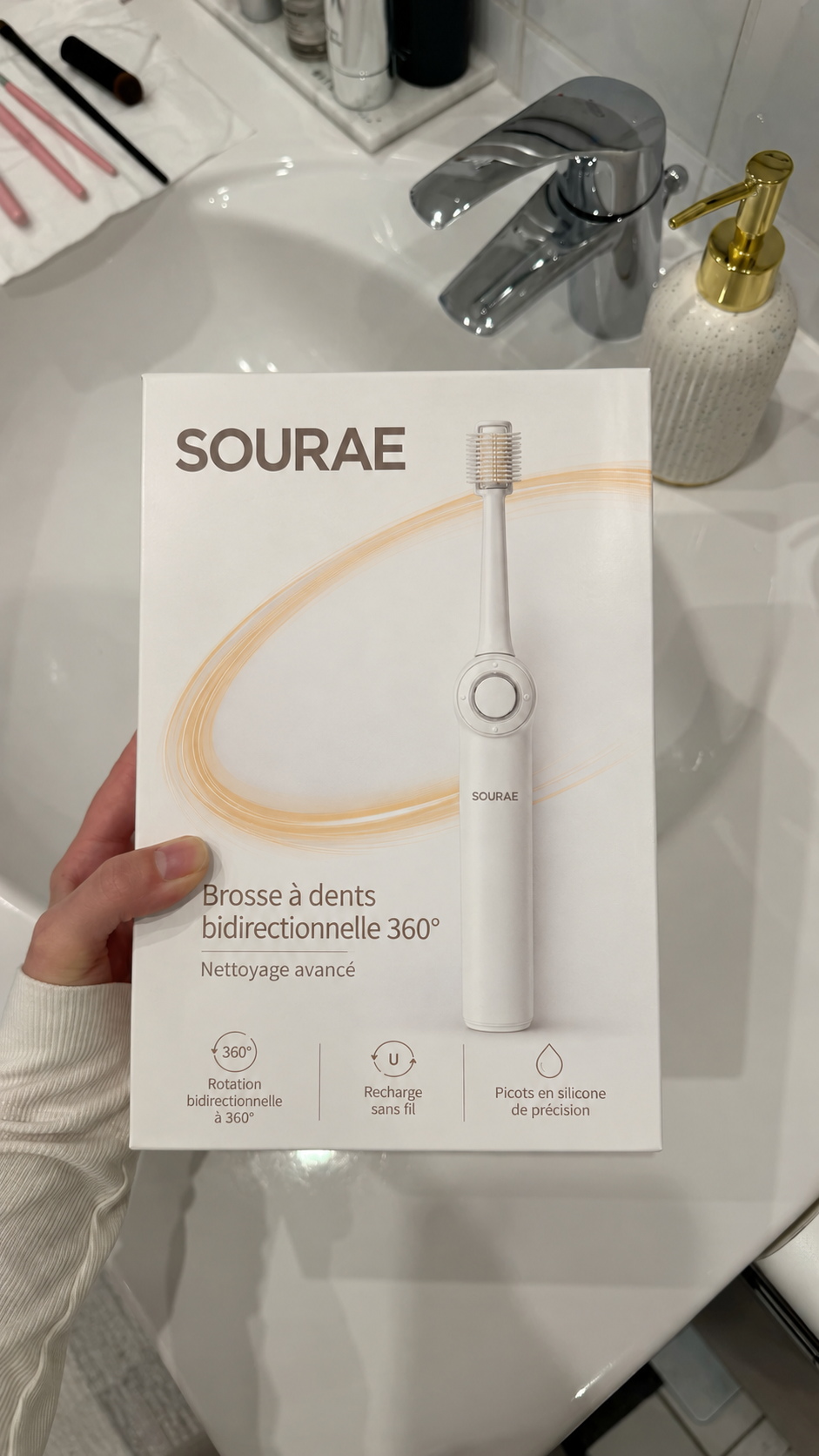 Boîte fermée de la brosse Sourae tenue devant un lavabo