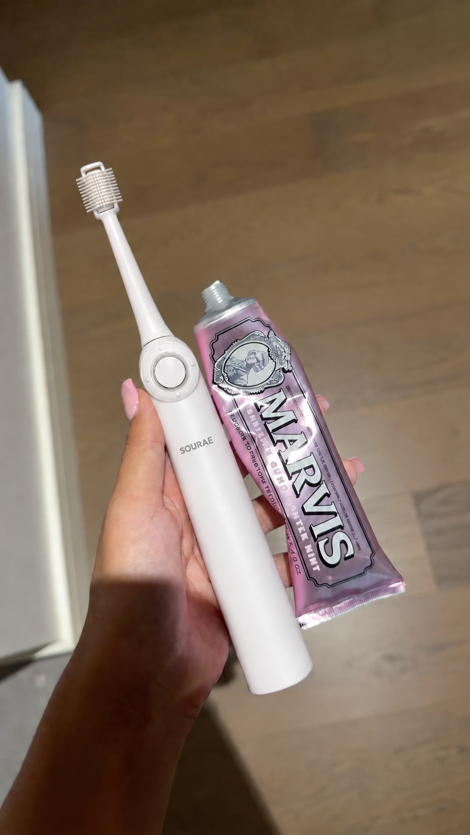 Brosse Sourae et tube de dentifrice tenus en main